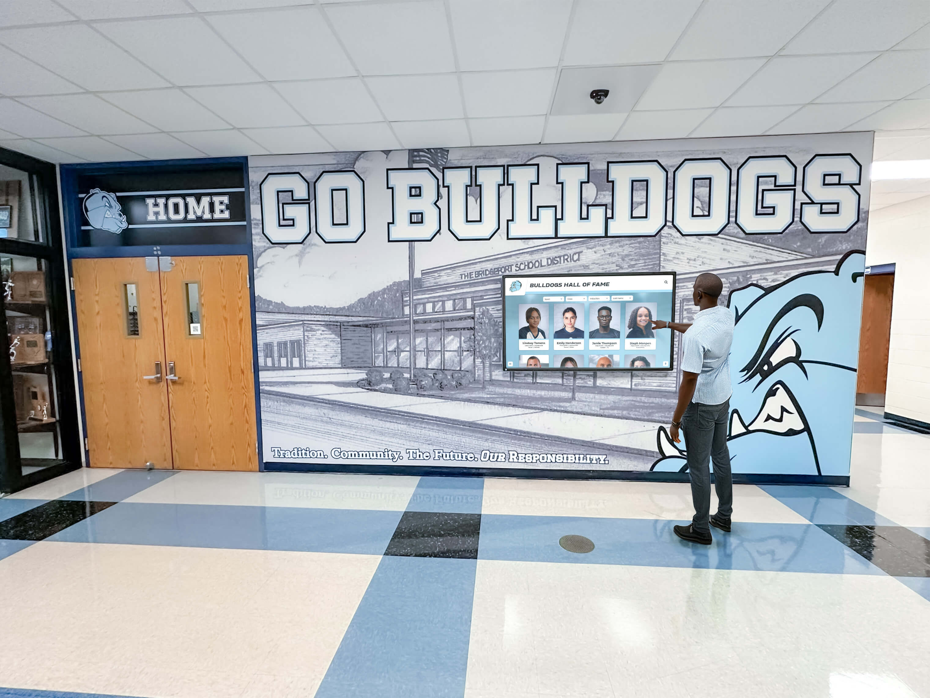 Man interacting with Bulldogs Hall of Fame touchscreen display in school hallway